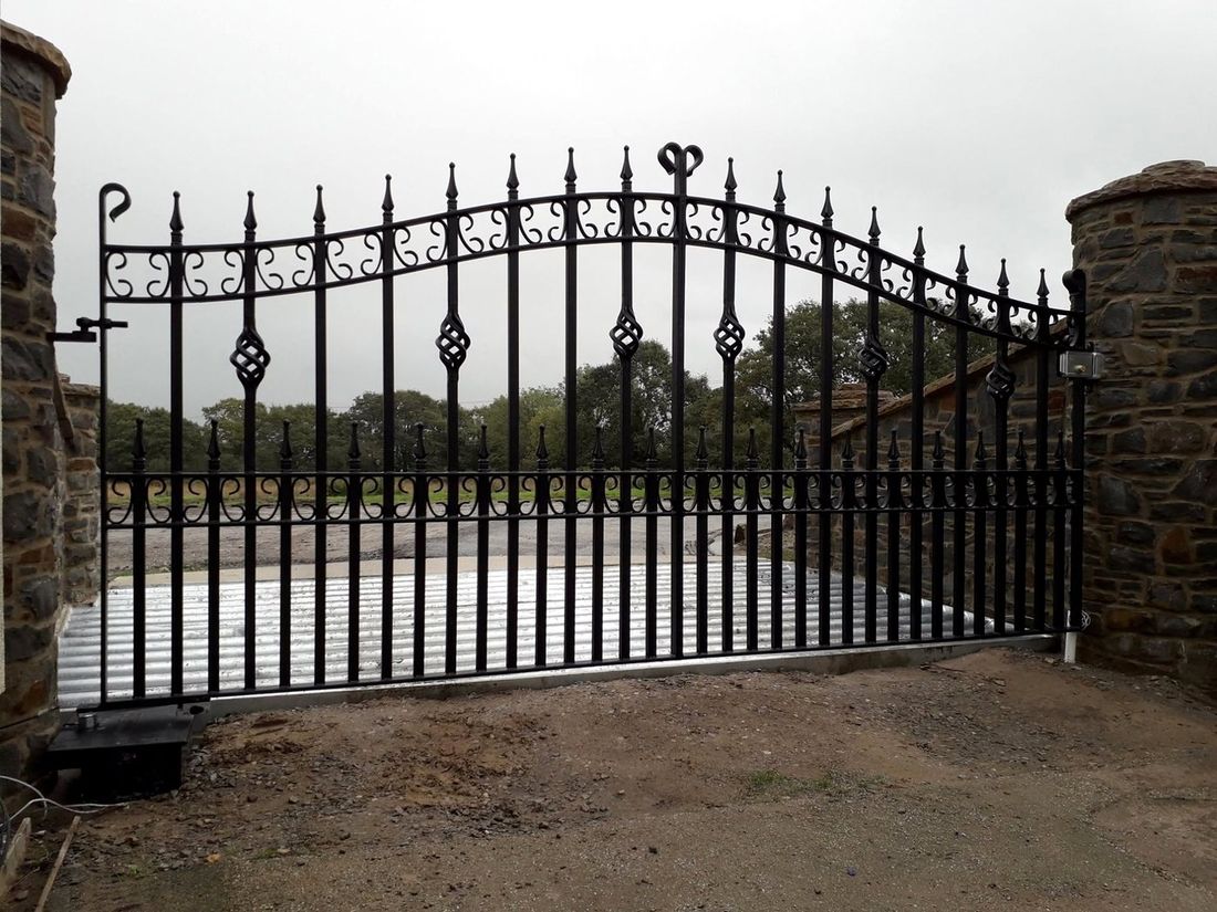 Large automated sliding wrought iron gate with spear tops and cage twists