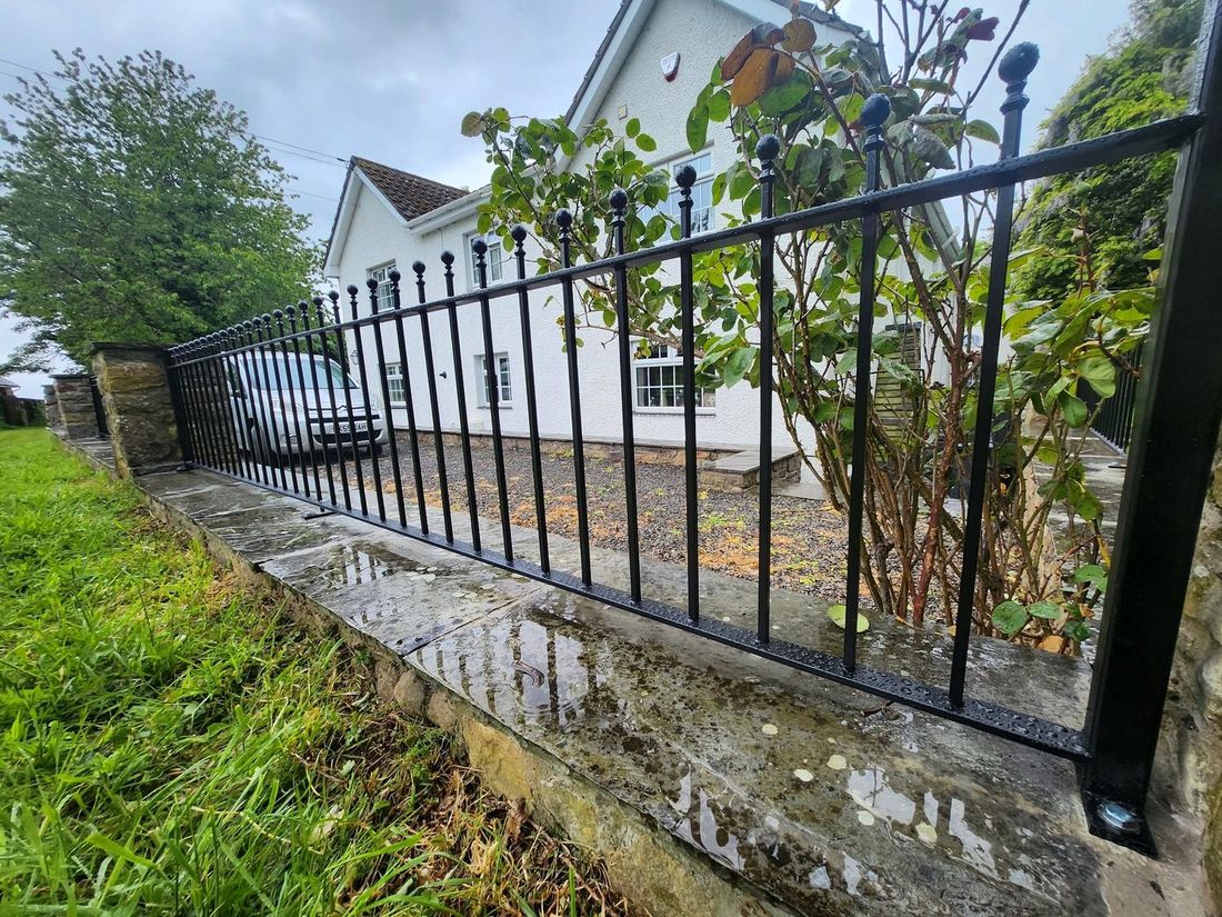 Ball-top wrought iron railings on a stone boundary wall
