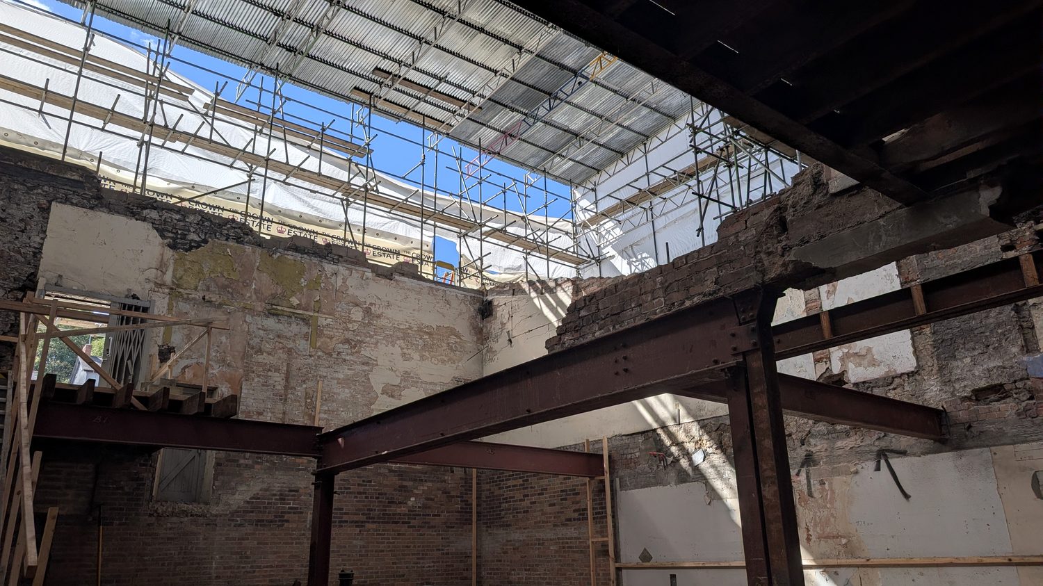 Structural steelwork spanning a large mixed-use development site behind scaffold