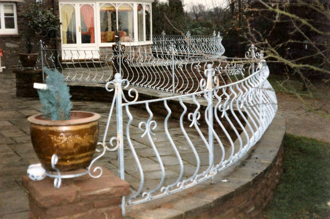 White-painted wrought iron scroll railings around a raised stone terrace